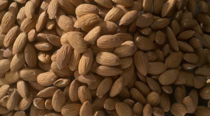 a close-up image of a pile of overflowing almonds